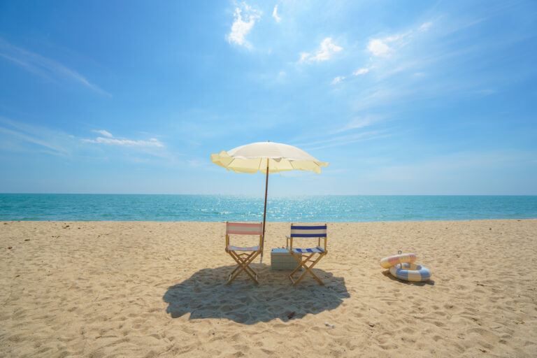 Beach chairs on a sunny sandy beach facing the ocean