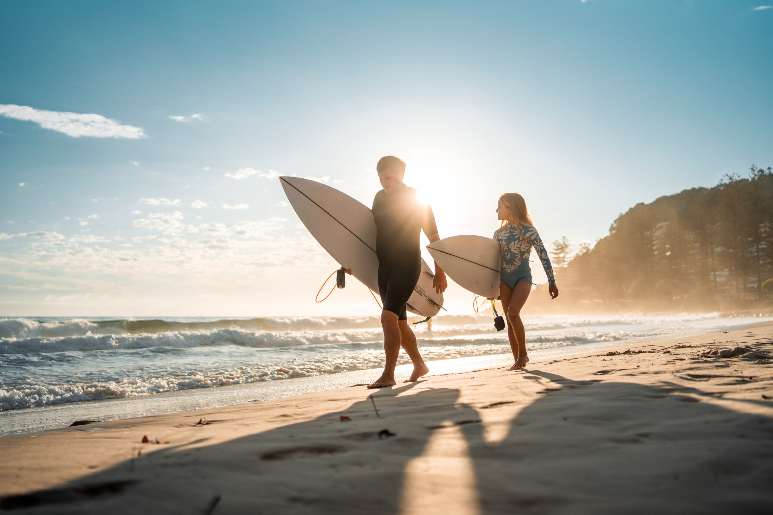 Father and daughter with surfboards at beach